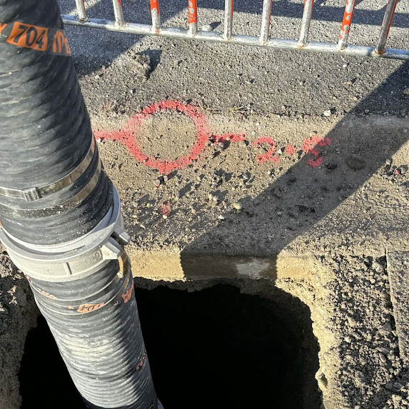 Close-up of pipe location marking at excavation point